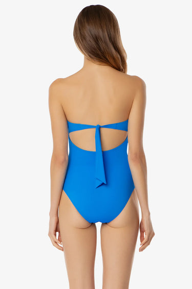 Woman wearing a blue strapless swimsuit with cut-out design on a white background