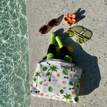  a white medium pouch with a tropical flamingo print next to a pool