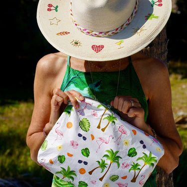 a woman holding a white medium pouch with a tropical flamingo print
