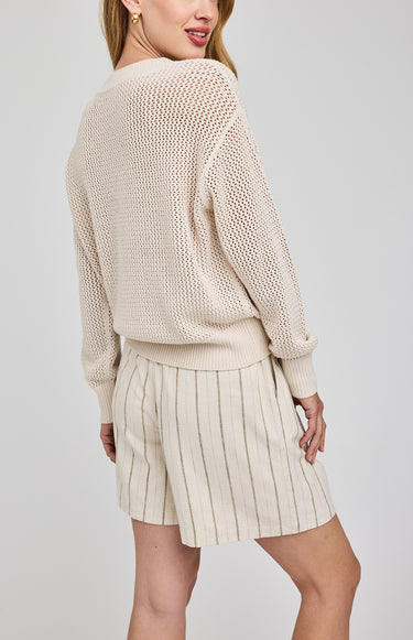 Woman wearing a beige knitted sweater and skirt set on a plain background