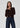 a woman wearing a dark brown cardigan and dark blue jeans on a white background