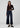 a woman wearing a dark brown cardigan and dark blue jeans on a white background