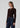 a woman wearing a dark brown cardigan and dark blue jeans on a white background