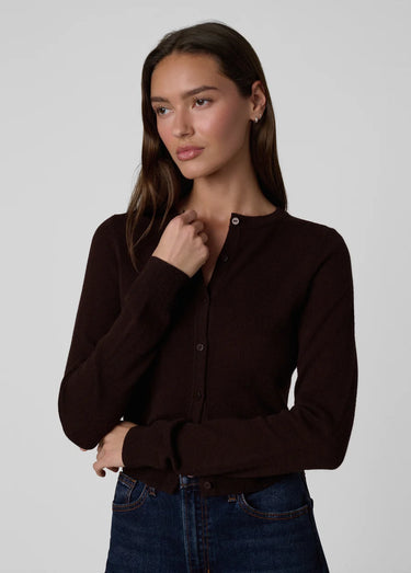 a woman wearing a dark brown cardigan and dark blue jeans on a white background