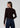 a woman wearing a dark brown cardigan and dark blue jeans on a white background