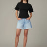 Woman wearing a black t-shirt and light blue denim shorts on a gray background