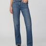 Person wearing blue jeans and black shoes on a white background