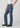 Person wearing blue jeans and black shoes on a white background