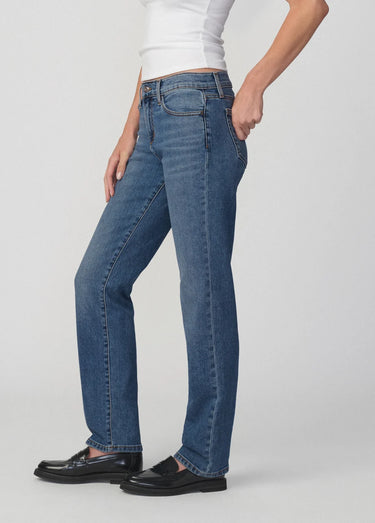 Person wearing blue jeans and black shoes on a white background