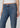 Close-up of a person wearing blue denim jeans with a white cropped top, shown against a light gray studio background.