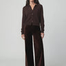 Chocolate brown button-front cardigan styled with matching wide-leg velvet pants and pointed-toe shoes on a model.