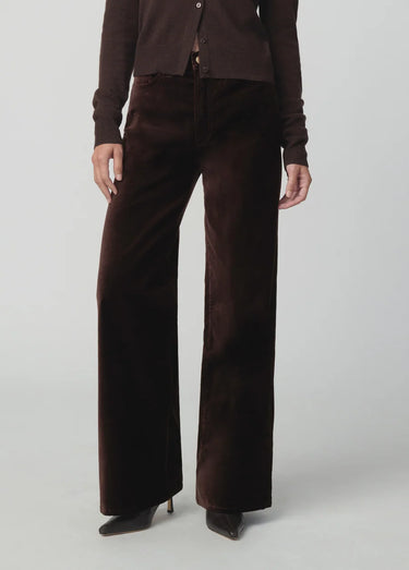 Chocolate brown button-front cardigan styled with matching wide-leg velvet pants and pointed-toe shoes on a model.