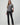 Black slim bootcut jeans styled with a metallic silver top and pointed-toe black heels on a model.