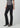 Black slim bootcut jeans styled with a metallic silver top and pointed-toe black heels on a model.