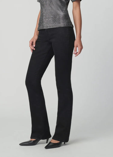 Black slim bootcut jeans styled with a metallic silver top and pointed-toe black heels on a model.