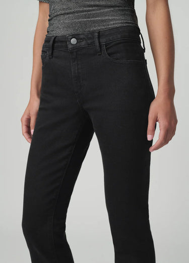 Black slim bootcut jeans styled with a metallic silver top and pointed-toe black heels on a model.