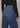 Person wearing blue jeans and a black sweater on a neutral background