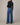 Person wearing blue jeans and a black top on a plain background