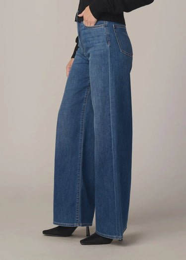 Person wearing blue wide-leg jeans on a plain background
