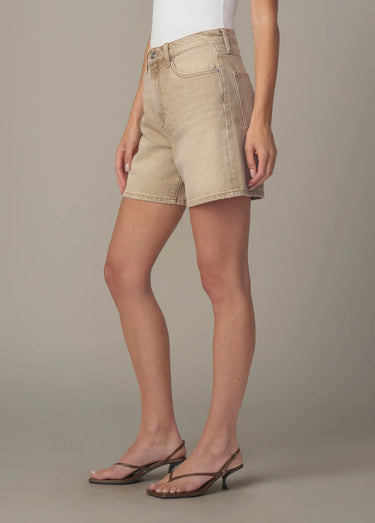 A woman wearing relaxed fit tan shorts