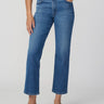 A model wearing a pair of medium-wash blue cropped jeans with a brown belt, paired with a white top and brown slingback flats, against a light gray studio background.