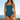 Woman wearing a teal swimsuit with a blurred beach background