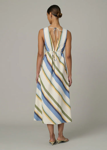 Woman wearing a striped dress with a deep neckline on a plain background