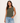 Woman wearing a green sleeveless top and blue jeans on a white background