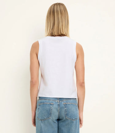 Person wearing a white sleeveless top and blue jeans on a plain background