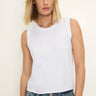 Woman wearing a white sleeveless top against a plain background