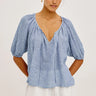 Woman wearing a barletta stripe blouse with puffed sleeves on a white background