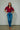 Woman wearing a red blouse and blue jeans against a plain background