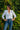 Woman wearing a white blouse and blue jeans standing against a green leafy background