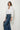 Woman wearing a white blouse and blue jeans against a white background