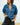 Woman wearing a blue denim shirt and black pants against a plain background