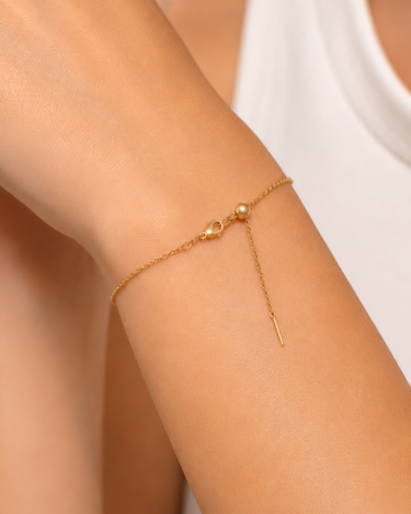 A close up of a woman’s wrist wearing a dainty chain adjustable bracelet