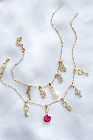 Two charm bracelets on a neutral background