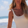 A woman wearing a floppy green hat on the beach