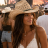 Woman wearing a straw cowboy hat at a concert with a crowd in the background