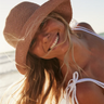 Woman wearing a straw hat and white bikini top on a sunny day.