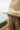 Close-up of a person wearing a straw hat with a ribbon and button, blurred background