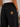 Close-up of a person wearing black sweatpants with a gold embroidered star patch on the back pocket, shown from the waist down.