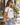 A woman wearing a white graphic t-shirt with 'LOVE' and a small rose design, paired with light blue jeans, sunglasses, and a woven straw bag, holding a coffee cup on a sunny street.