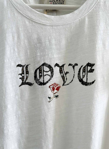 White t-shirt with 'LOVE' text and a rose graphic on a hanger.
