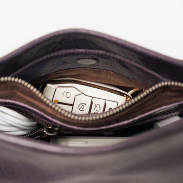 Close-up of a car key fob inside an open purple leather bag.
