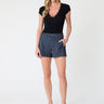 Woman wearing a black top and denim shorts on a white background