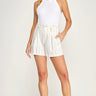 A woman wearing a white tank top and white and navy stripe shorts