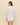 Woman wearing a white shirt with sheer panels on a beige background