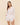 Woman wearing a white linen shirt and shorts on a beige background
