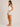 Woman wearing a white tank top and beige shorts on a plain background